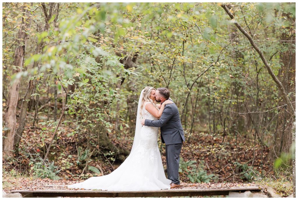 Bride and groom kissing in forest  at the Shed at Quiet Hollow in Maiden, NC by Charlotte wedding photographer, Jacqueline Jones