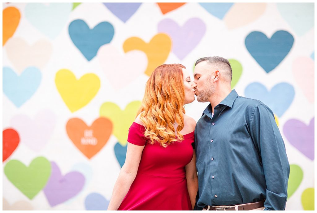 Engaged couple kissing at the Heart Confetti Wall in Charlotte, NC, by Charlotte engagement photographer, Jacqueline Jones