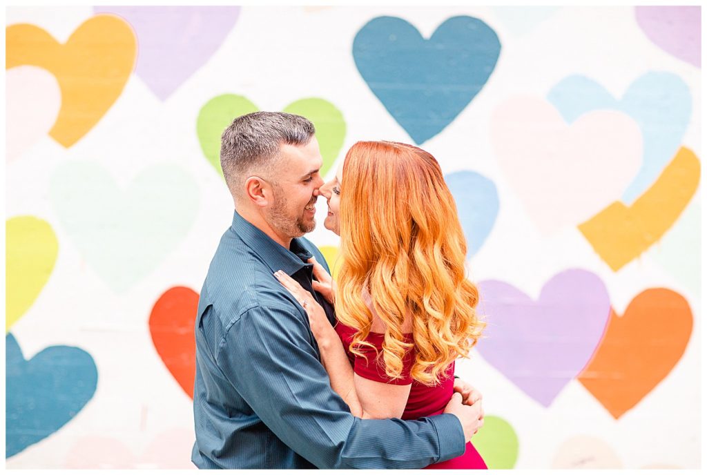 Engaged couple hugging at the Heart Confetti Wall in Charlotte, NC, by Charlotte engagement photographer, Jacqueline Jones