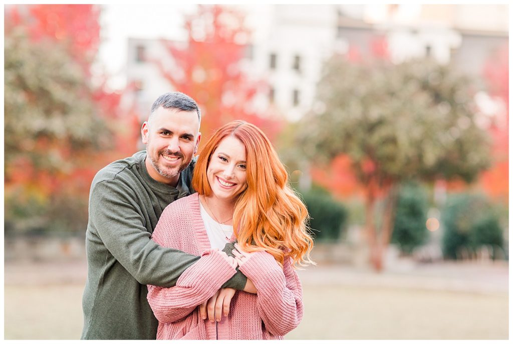 Engaged couple smiling at the Romare Bearden Park in Charlotte, NC, by Charlotte engagement photographer, Jacqueline Jones