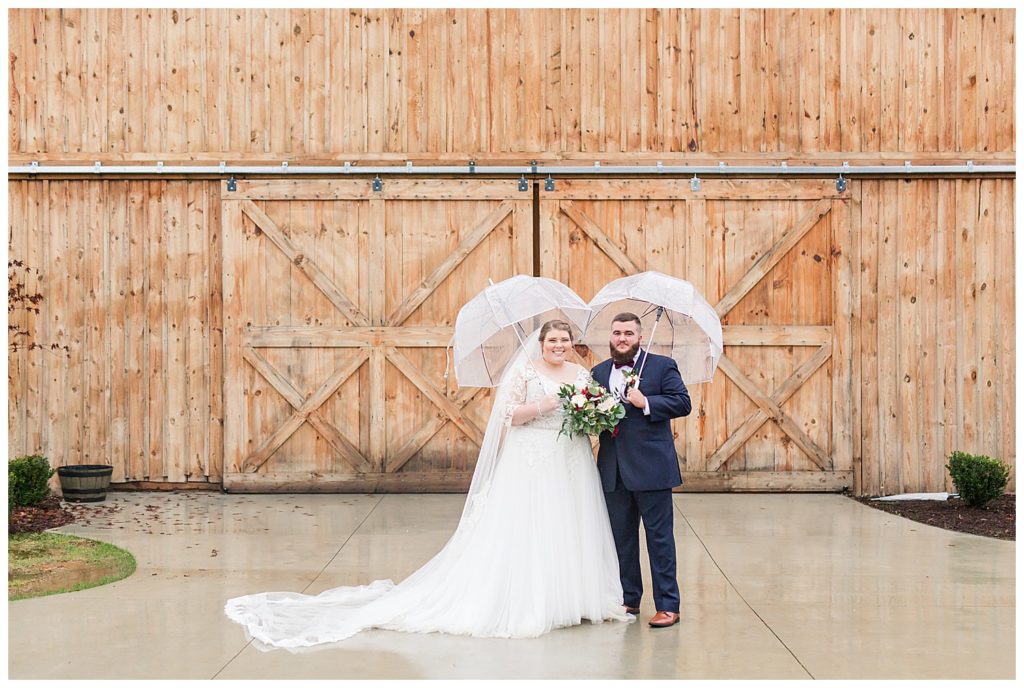 Bride and groom in the rain with umbrellas at the Barn at Sandcastle Farm in Dallas, NC by Charlotte wedding photographer, Jacqueline Jones 