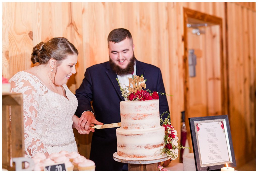 Bride and groom cutting the naked-style wedding cake at the Barn at Sandcastle Farm in Dallas, NC by Charlotte wedding photographer, Jacqueline Jones