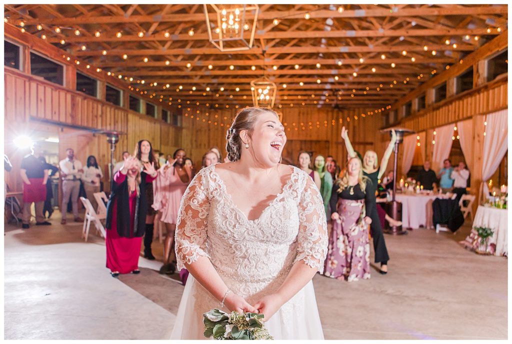 Bride laughing and throwing bouquet at the Barn at Sandcastle Farm in Dallas, NC by Charlotte wedding photographer, Jacqueline Jones