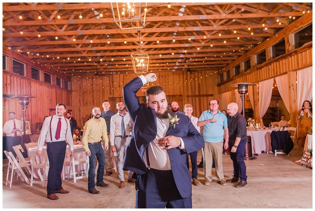 Groom throwing bride’s garter at the Barn at Sandcastle Farm in Dallas, NC by Charlotte wedding photographer, Jacqueline Jones