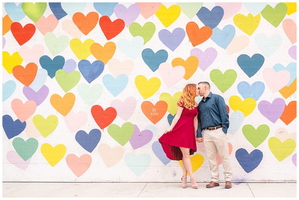 Couple kissing at the Confetti Hearts Wall in Charlotte, NC, by Charlotte engagement photographer, Jacqueline Jones